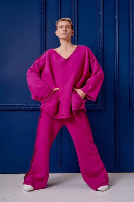 Męskie spodnie Sztosy Fuksja oversize w streetwearowym zestawie z bluzą Sigma na tle niebieskiej ściany.