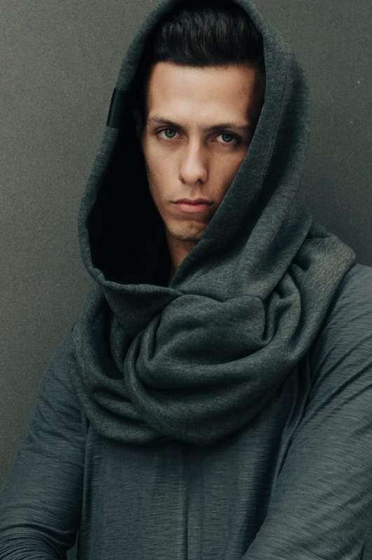 Mężczyzna w dzianinowym kapturze Ciemnym Męskim w grafitowym odcieniu na miejskim tle